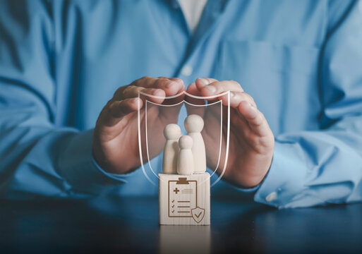 Hands protecting wooden family figures with medical shield icon. Life insurance, health protection, financial security planning, and accident coverage for family welfare and safety concept.