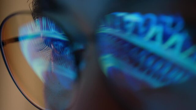 An automation engineer wearing eyeglasses studies a display with digital gears reflected on the lenses, symbolizing smart manufacturing, process automation, engineering precision, and Industry 4.0.
