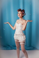 Obraz premium Joyful moment of a woman in a vintage hairstyle amidst floating bubbles in a cheerful blue setting