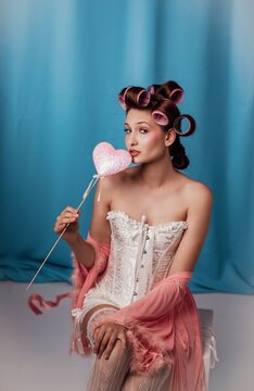 Delightful beauty with retro curls enjoying a sweet treat against a dreamy blue backdrop