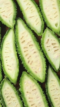 Halved fresh bitter melons arranged side by side, rotating, Top view shot