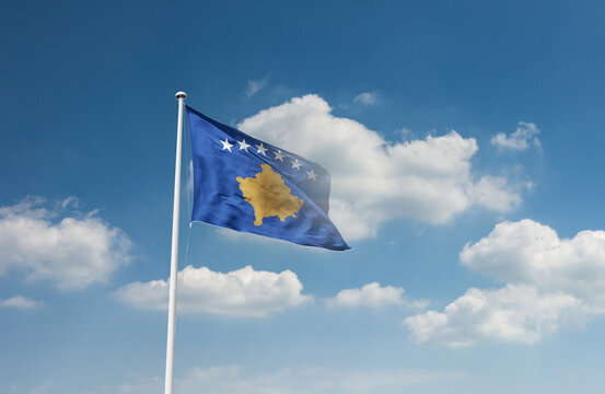 Kosovo flag waving in beautiful sky.