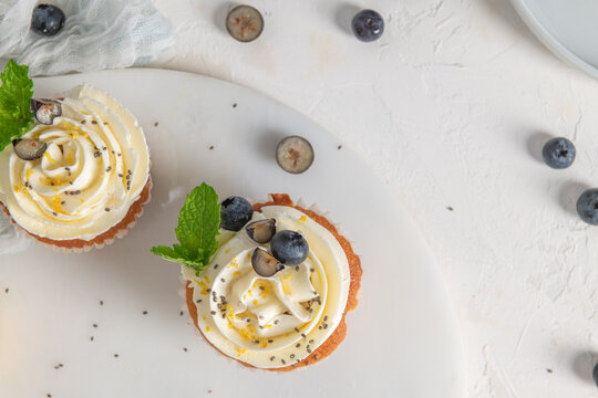 Fresh lemon cupcakes with white cream frosting, blueberries, and mint leaves