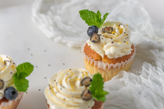 Fresh lemon cupcakes with white cream frosting, blueberries, and mint leaves