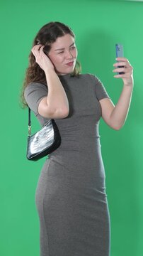 Csmiling pretty girl takes selfie on a green background. Chroma key compositing. . High quality 4k footage