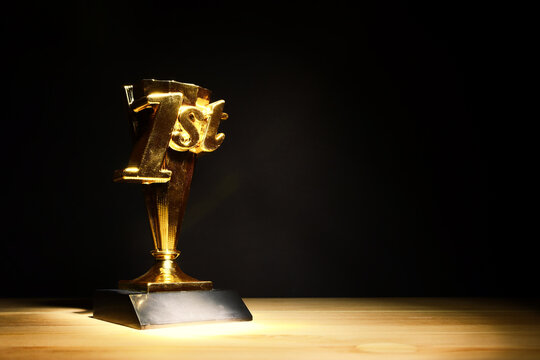 Golden trophy on wooden table and dark background. Idea of award and success