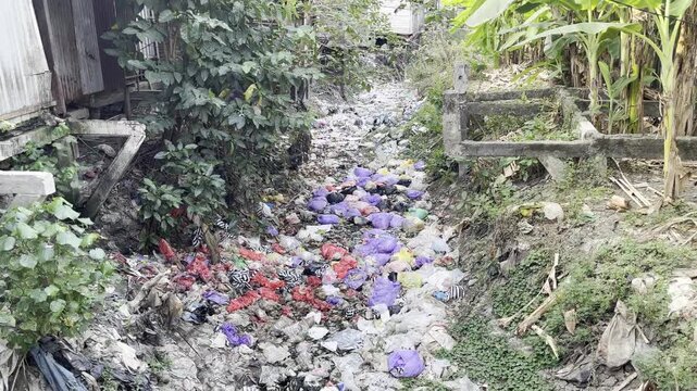 Environmental pollution with colorful plastic garbage in countryside ditch