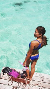 Swimming girl with diving mask and snorkel fins in tropical ocean travel vacation. Sport activity lifestyle in paradise. Raw unedited vertical video of real unretouched woman model without any makeup