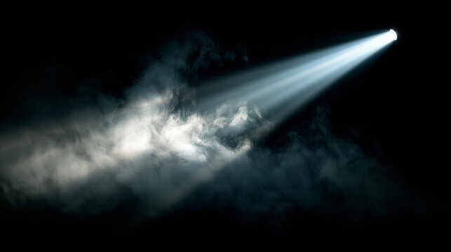Bright beam of spotlight shining through smoke on black background