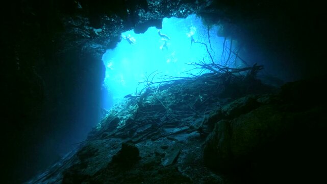 Wide underwater scene framed by darkness with a bright opening and rocky foreground in Cenote Carwash, Quintana Roo, Mexico.