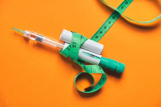 Glp-1 injection pen and tape measure symbolizing weight loss and obesity treatment