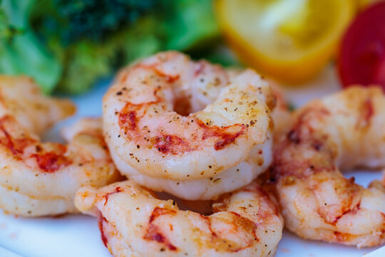 Macro close up of grilled tiger prawns seasoned with black pepper served with fresh vegetables, seafood dish concept