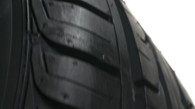 Tenacious Tread in Fast Spin. Car wheel slowly rotates in front of the camera close-up on a white background