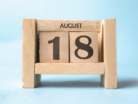 A wooden block calendar for August 18th on a light blue background.