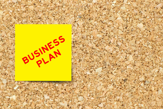 Yellow note paper with word business plan on cork board background with copy space