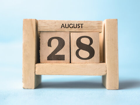 A wooden block calendar for August 28th on a light blue background.