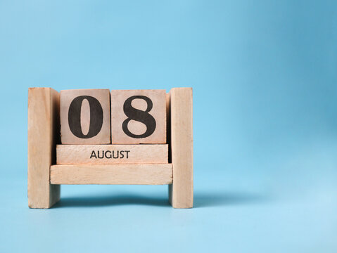 A wooden block calendar for August 8th on a light blue background.