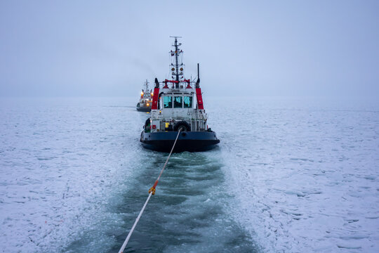 Tugboat Towing Rope Through Ice-Covered Frozen Sea, Maritime Winter Icebreaking Operation. Winter Maritime Logistics and Navigation in Frozen Cold Water, Marine Transportation