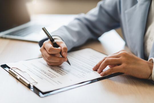 Extreme close up of businessman signing official document with black pen.