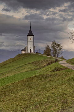 St.Primus and Felician hilltop Gothic church on a grassy ridge backed by the Karavanke mountains, on a cloudy autumn afternoon. Jamnik-Slovenia-173