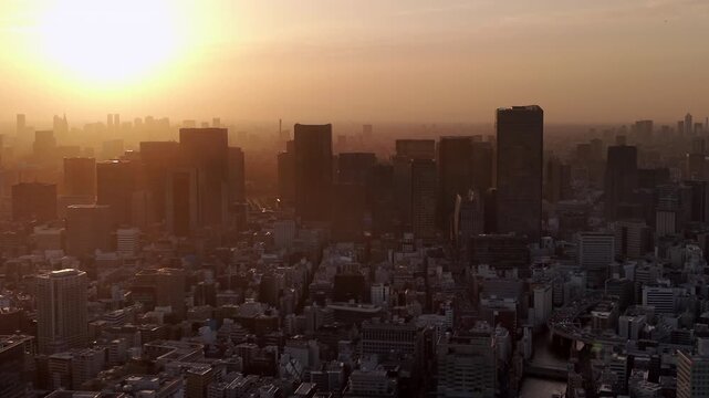 Aerial view of Tokyo cityscape with high rise buildings silhouetted against the bright sky, Japan.