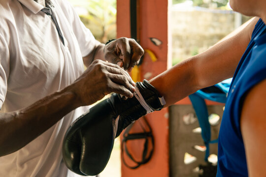 Adult helping youth wrapping boxing glove for training