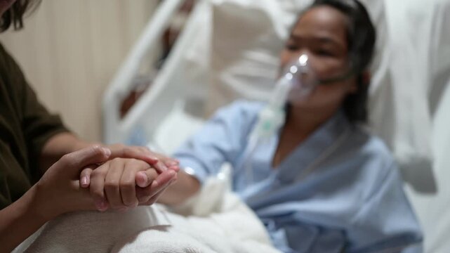 A concerned mother holds her sick child's hand while the child receives oxygen therapy in a hospital bed. Family support, pediatric healthcare, compassion, medical treatment, and hope for recovery.