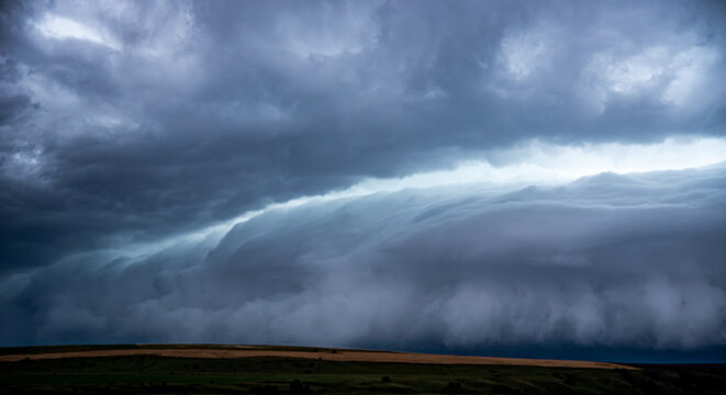 Dramatic landscape featuring a massive shelf cloud of a supercell thunderstorm moving over a rural road and countryside fields, capturing the powerful atmosphere of an approaching storm.