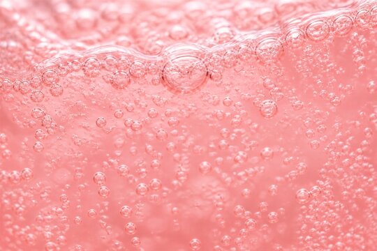 Carbonated beverage showing bubbles in pink liquid closeup