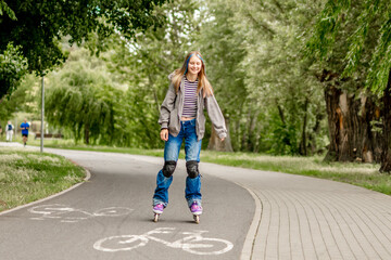 Fototapeta premium Young girl with blonde hair inline skates on a paved park path during daytime.