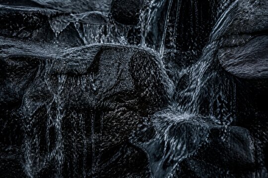 Dark rock surface with flowing water in low light setting