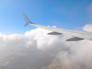 Fototapeta premium View from an Airplane Window with Wing and Clouds. Passenger Window View of Aircraft Wing in the Sky. Scenic Flight View with Airplane Wing and Clouds.