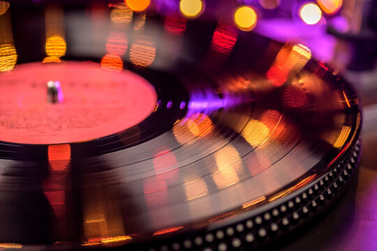 Vinyl record spinning on turntable with bokeh lights