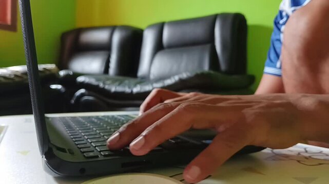 Business professional typing on laptop in modern office. Young male freelancer working remotely on computer with ergonomic setup.