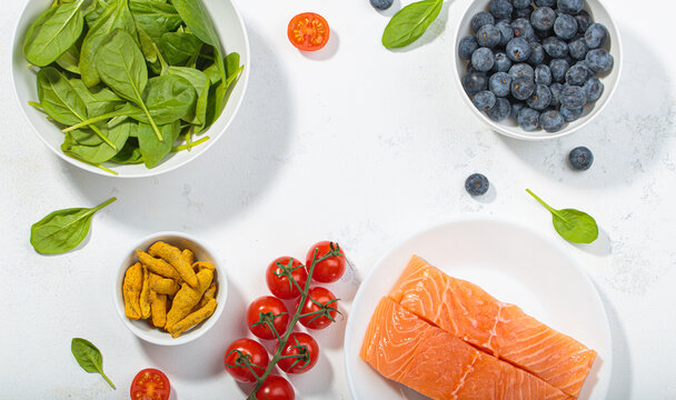Healthy anti inflammatory diet food ingredients white background salmon blueberry spinach copy space