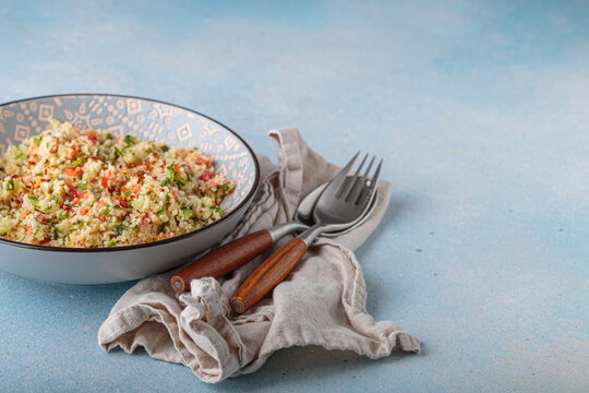 Tabbouleh salad couscous vegetables bowl Middle Eastern blue background copy space