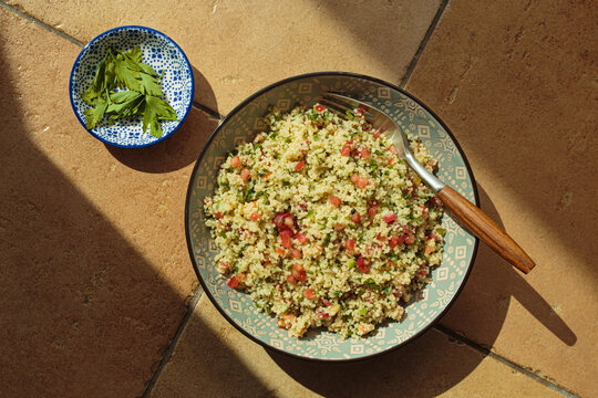 Tabbouleh salad couscous, vegetables top view natural sun light terracotta