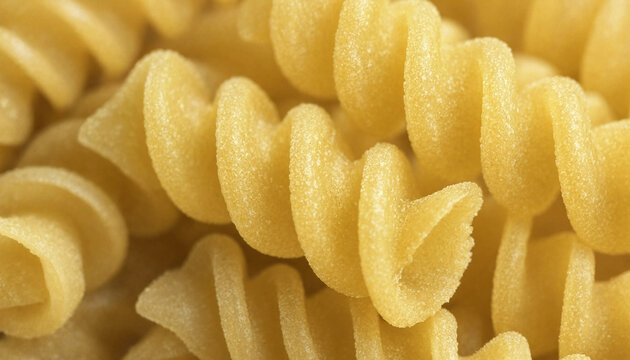 Macro close up of raw yellow fusilli pasta spirals arranged in a pile showing the textured surface and curved shape of the dry noodles