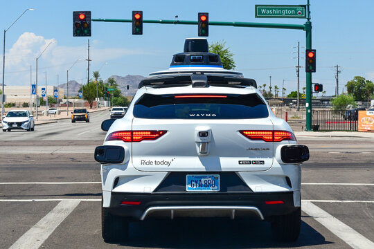 Waymo autonomous Jaguar electric taxi stopped at a traffic light on an urban roadway, illustrating self-driving technology, electric transportation, and commuter mobility