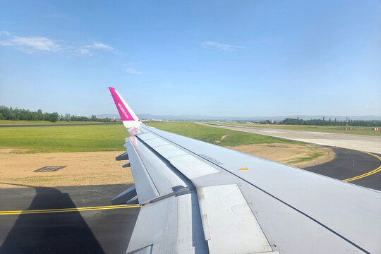 Basel, Switzerland, May 25, 2026: Aerial Perspective of Airplane Wing on Runway During Daytime Flight Takeoff