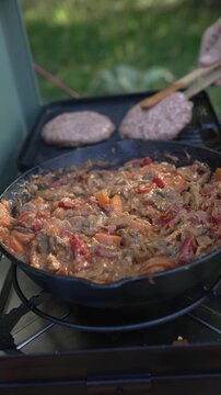 Person cooking beef stroganoff and hamburgers on camping stove