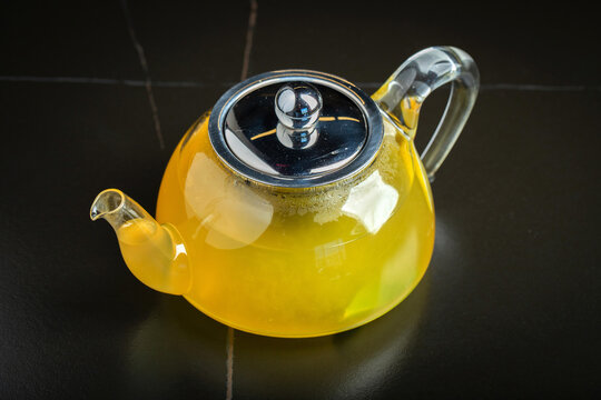 Fruit tea with mango and mint in a glass teapot on the table