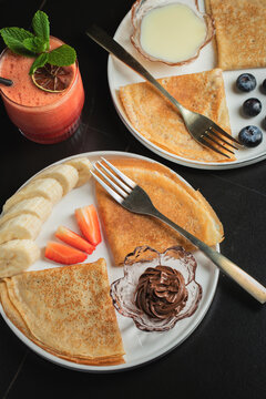 A plate of crepes filled with chocolate spread and topped with banana slices and mint