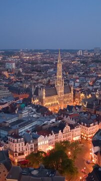 Vertical Aerial View of Brussels at dusk with illuminated buildings and a clear sky