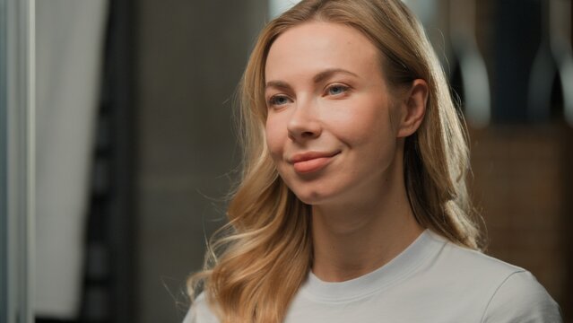 Close up pretty Caucasian middle-aged woman with perfect face skin make-up looking in mirror reflection smiling positive female with natural cosmetic lady smile pampering skincare at home bathroom