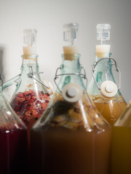 Bottles of Different Drinks Fermenting on a Table in Soft Light