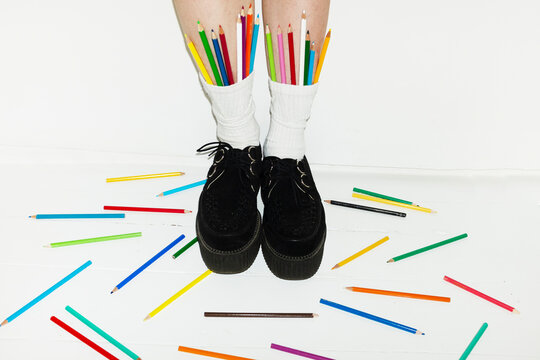 Person wearing fashion style shoes & sock full of colour art pencils