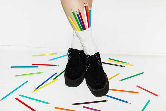 Person wearing fashion style shoes & sock full of colour art pencils