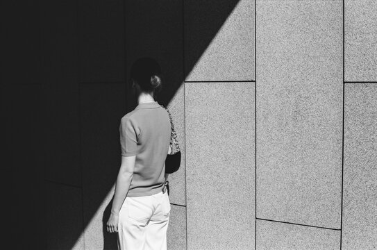 The young woman strolls through a city park on a sunny day. 

