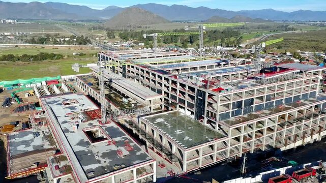 Aerial view of hospital construction progress with partially covered roof Keywords extra: roof covering, construction materials, dirt lot, building envelope